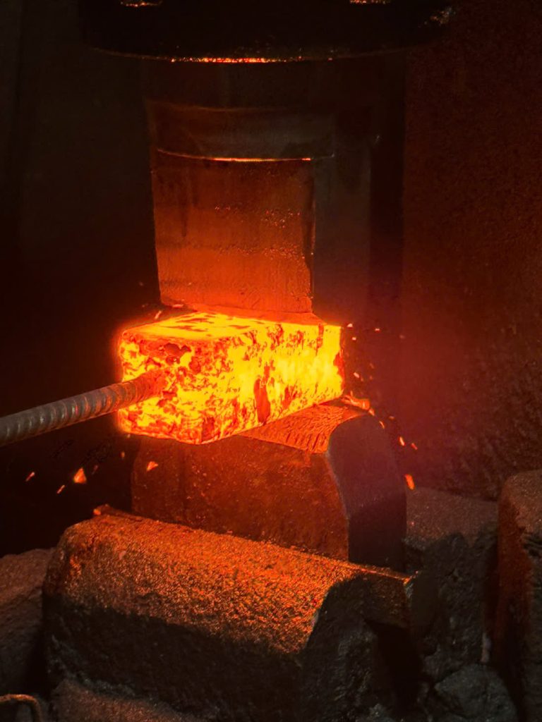 Phôi thép nung đỏ dưới búa máy trong xưởng rèn